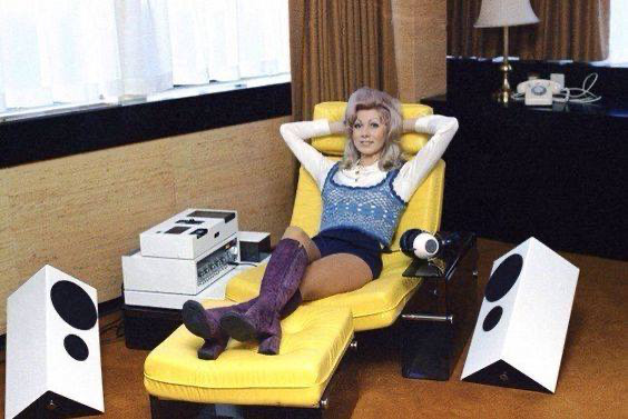 A woman reclining with speakers around her.